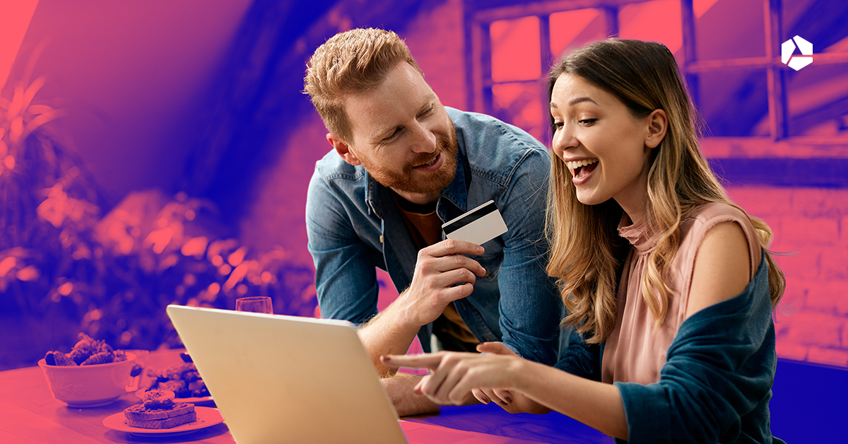 Een man en vrouw achter een laptop met een bankkaart in de hand.